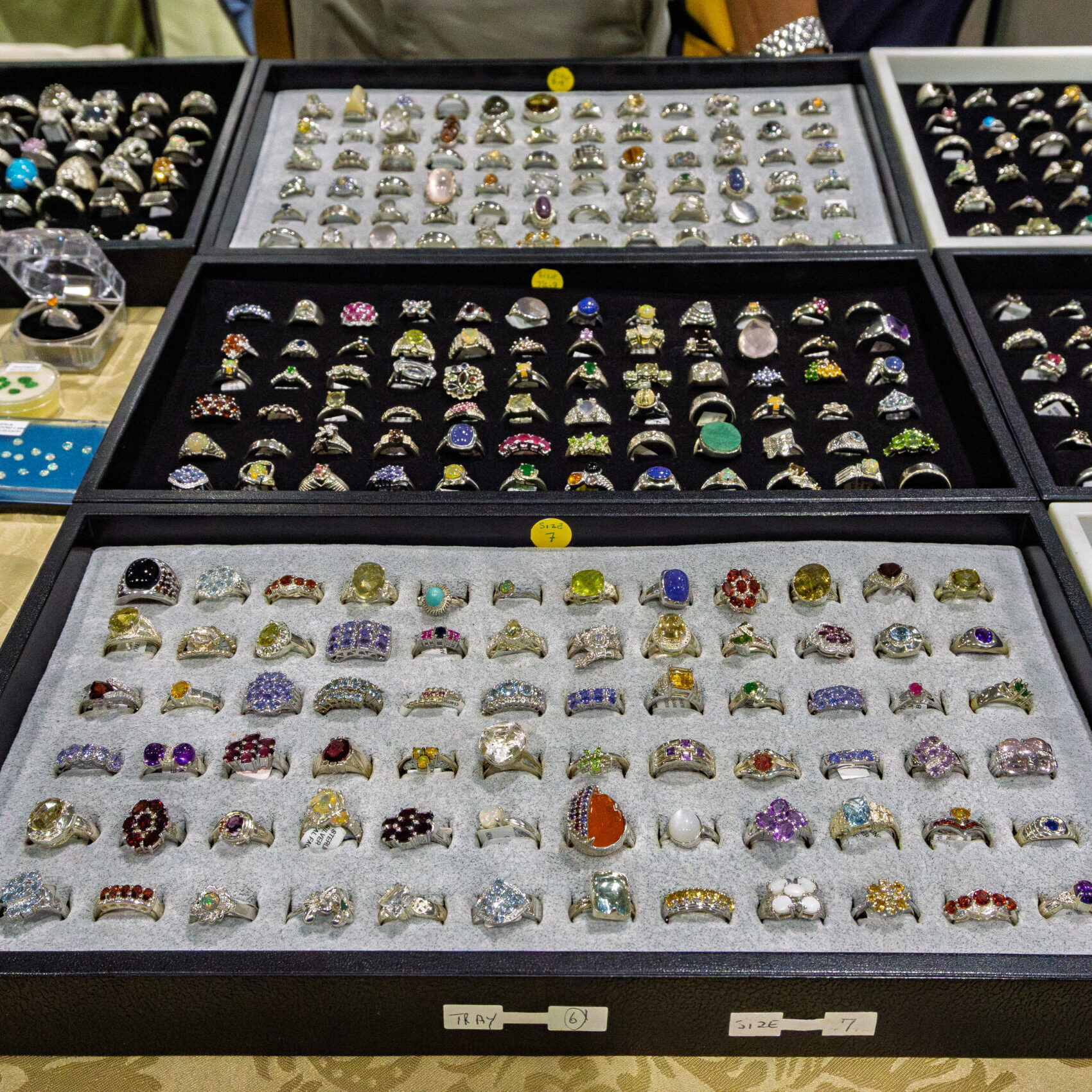 Handcrafted gemstone and crystal rings in vendor display cases at a Rock and Gem Expo