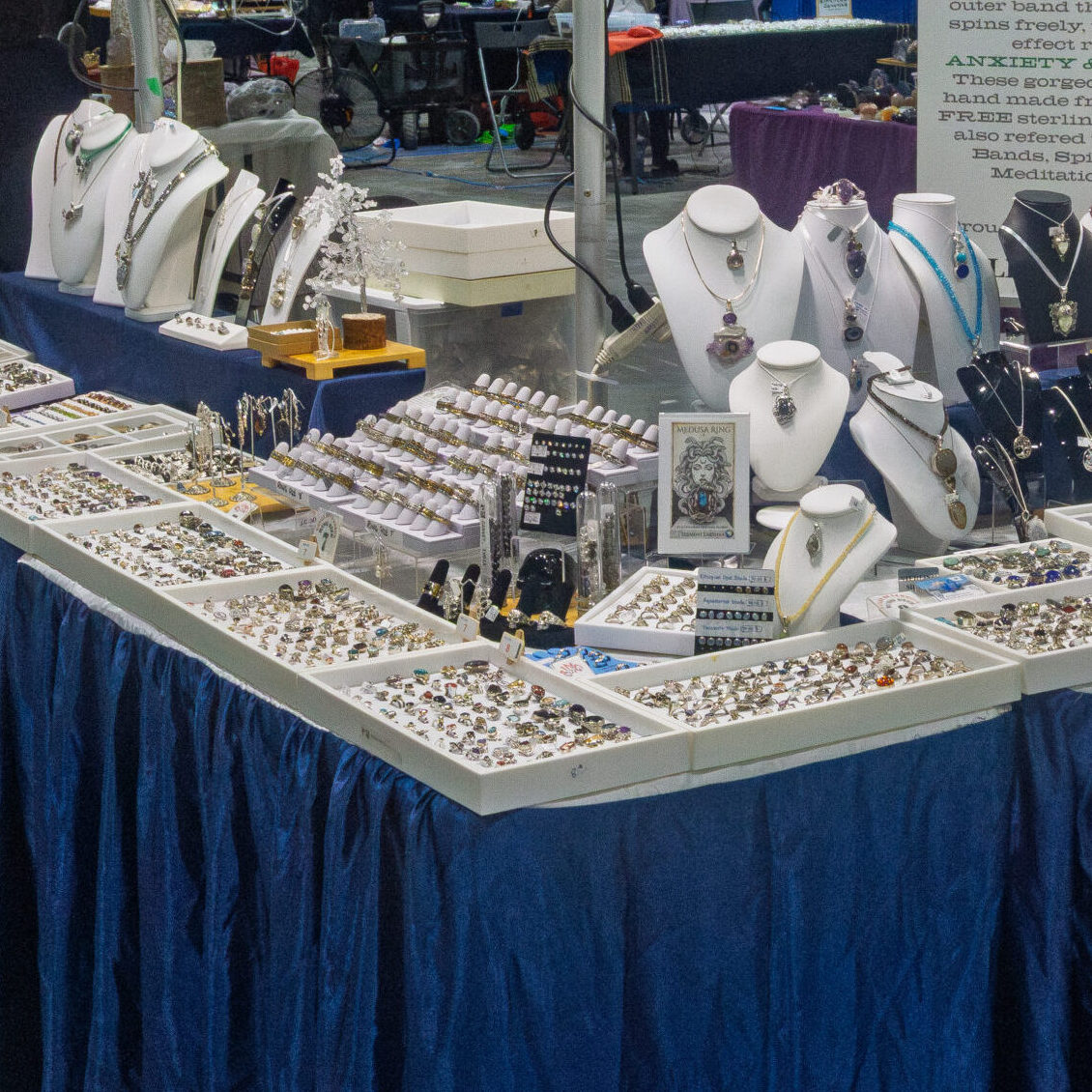Handcrafted gemstone necklaces and rings on display at a Rock & Gem Expo jewellery vendor table