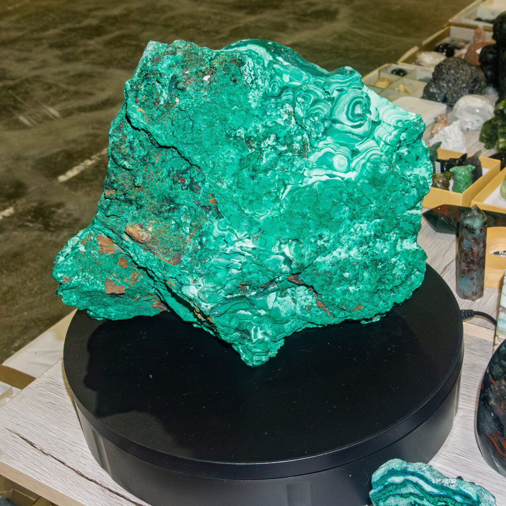 Large malachite mineral specimen displayed on a stand at Rock & Gem Expo