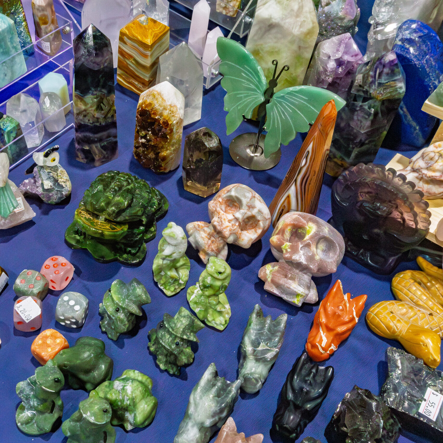 Colourful gemstone carvings, crystal figures and minerals on display at a Rock and Gem Expo vendor table