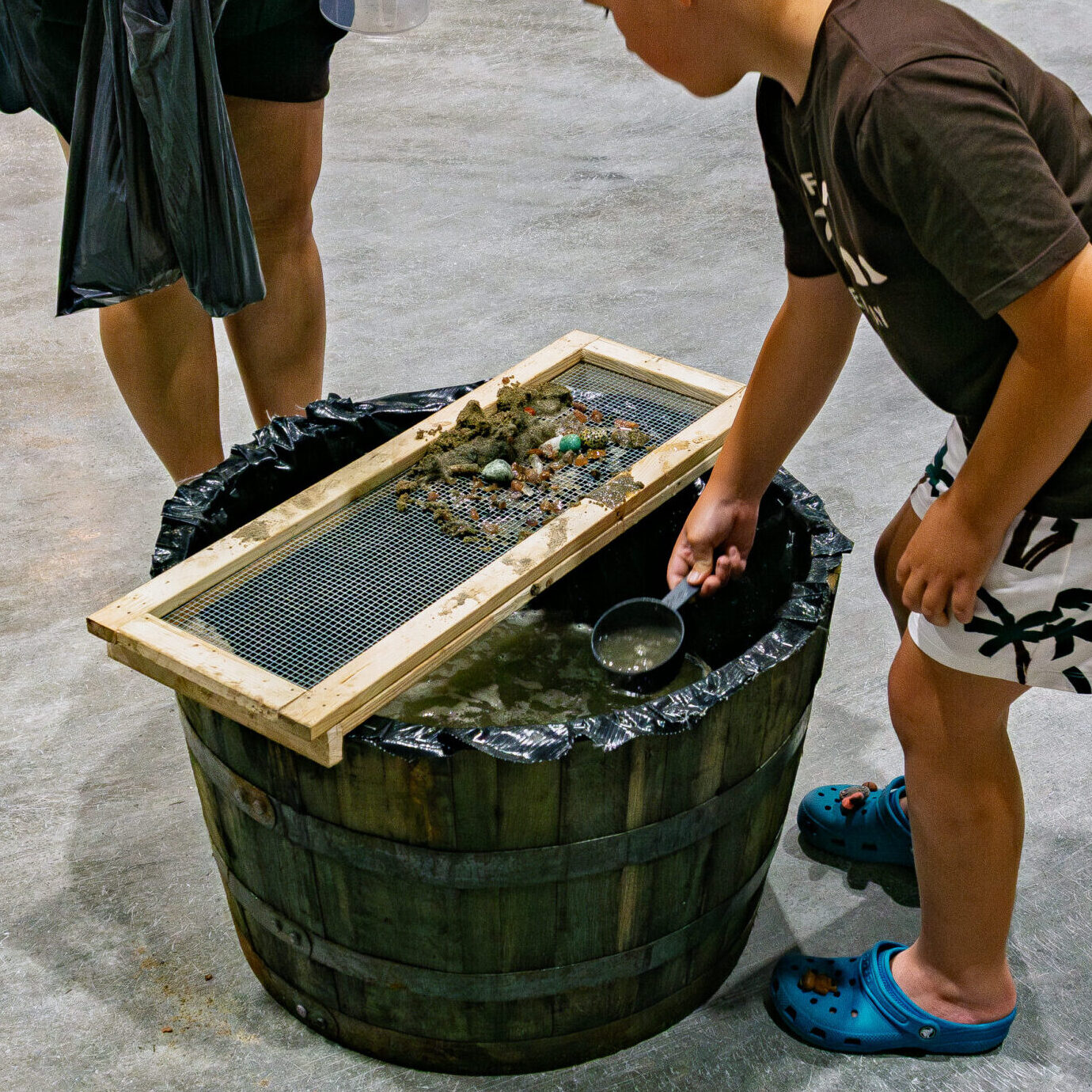 Child sifting sand and water to uncover gemstones at the Gem Sifting Station
