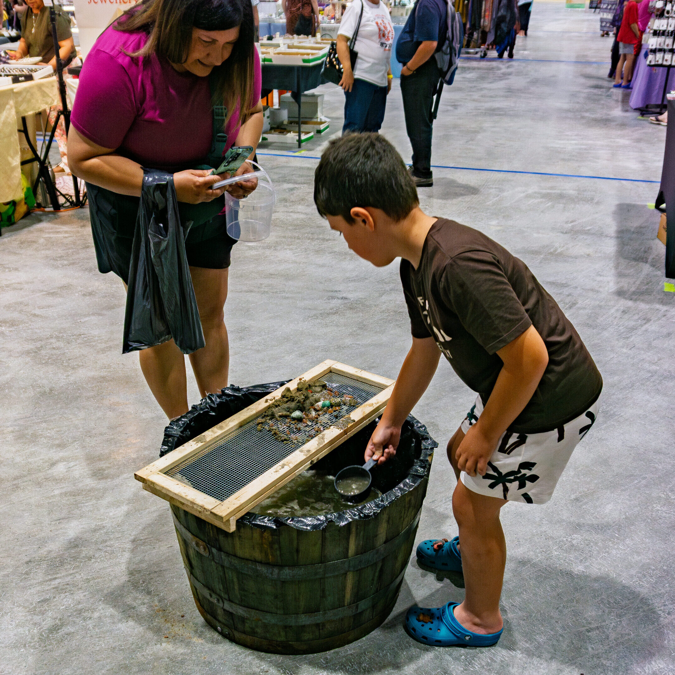 Child and parent discovering gemstones at the Rock and Gem Expo gem sifting station